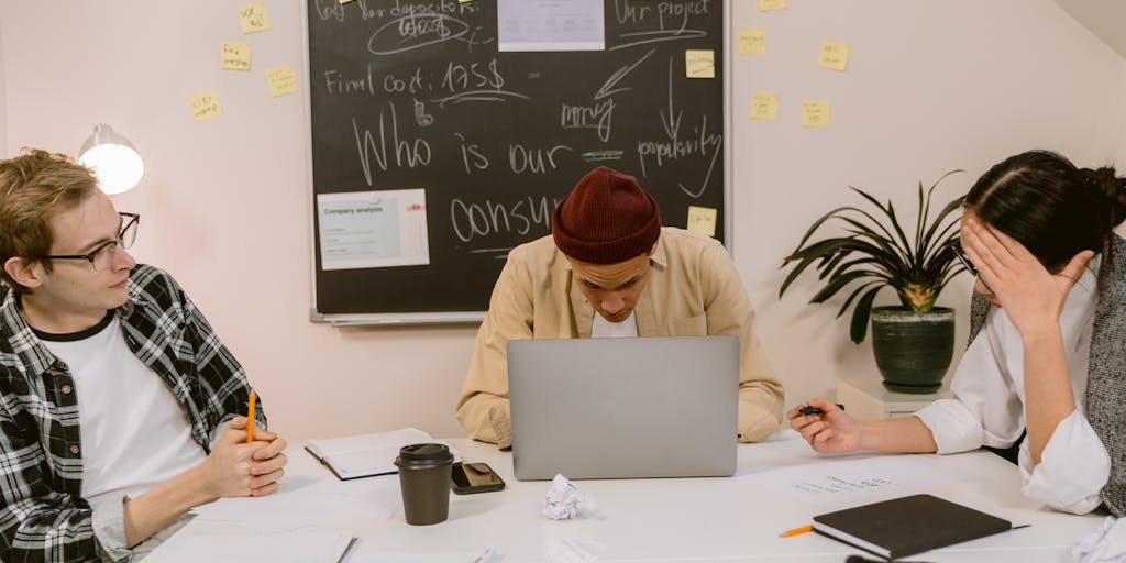 Over-the-shoulder shot of a marketer standing at a large whiteboard, actively drawing a color-coded topical map. The central node reads 'SEO' with radiating clusters labeled 'Keywords', 'Content', 'Backlinks', 'Technical', each cluster having sticky notes, arrows, and small icons. A laptop with analytics open sits on a nearby table, and a cup of coffee and scattered index cards add a real-workshop feel.