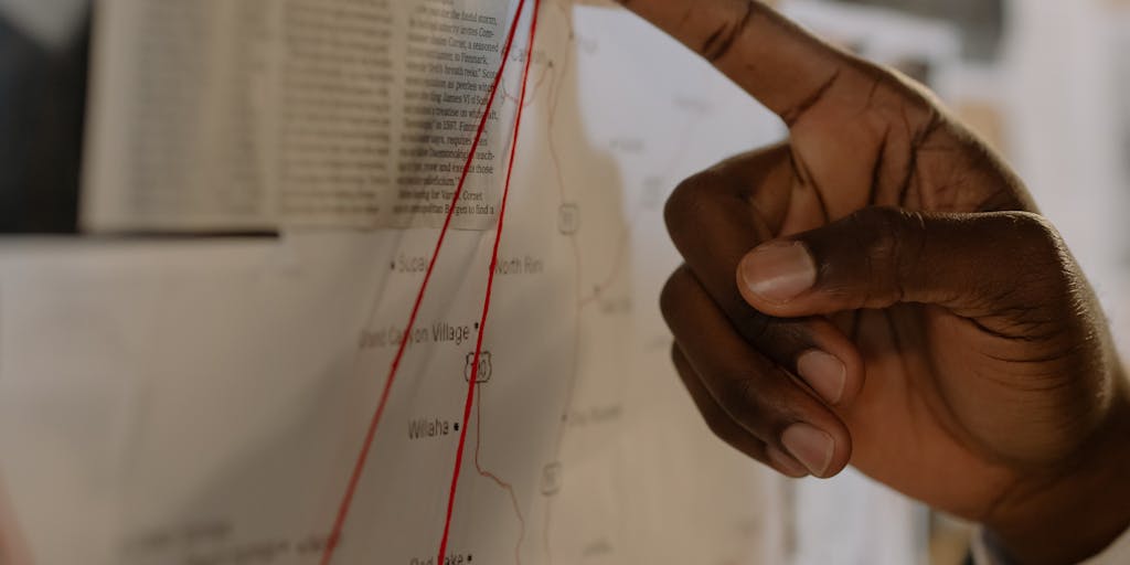 Close-up of hands assembling a physical puzzle on a corkboard where the completed center spells 'SEO' and surrounding puzzle pieces are labeled 'Content', 'Links', 'UX', 'Keywords'. Red map pins and string connect certain pieces, evoking a strategic topical map laid out like a detective board, with a slightly rustic, tactile aesthetic.