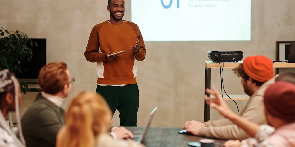 A diverse product team in a bright conference room gathered around a large screen showing a Google AI Overviews presentation—overview tiles, priority flags, and recommended actions. Team members are mid-discussion, pointing and taking notes. The composition captures collaboration and decision-making supported by AI summaries, with natural light and candid expressions.