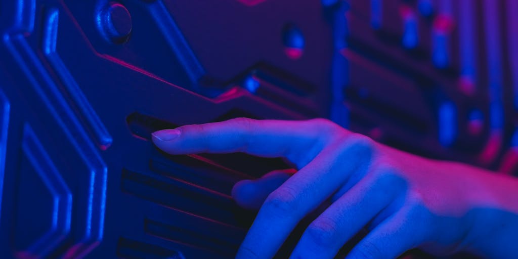 A dark, cinematic scene of a person standing at a small table, reaching out to touch a floating holographic interface labeled “AI Mode.” The hologram uses Google’s color palette (blue, red, yellow, green) as glowing panels and waveforms; translucent cards float around showing search results, suggestions, and graphs. Soft rim lighting highlights the subject’s silhouette while background monitors show blurred code and network maps to emphasize advanced intelligence.