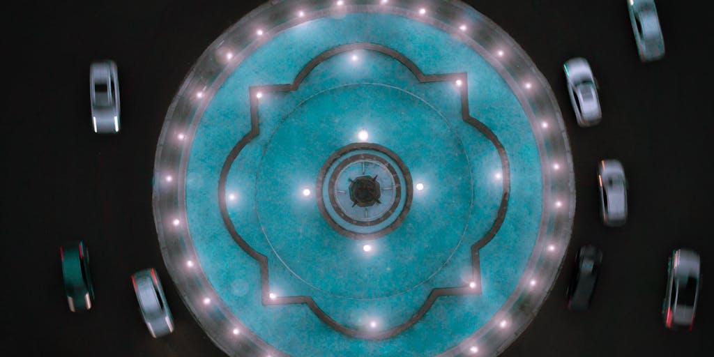A dynamic aerial/tilt shot of a traffic roundabout filled with cars going in circles with superimposed glowing arrows and translucent tags showing numbers like 301 → 302 → 307 to suggest a redirect chain or loop. Slight motion blur on the cars and a moody color grade emphasize confusion and the endless-loop problem.