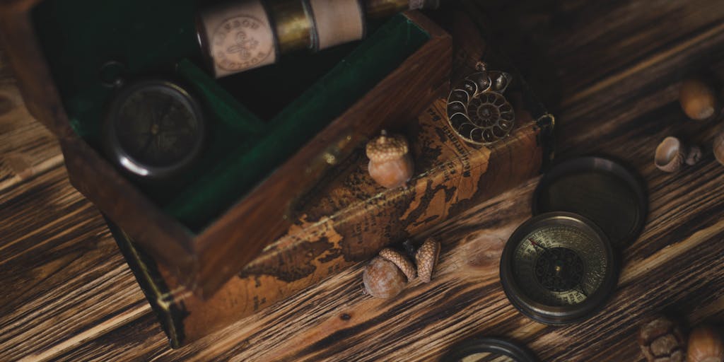 A creative still-life styled like a treasure map: several aged scrolls labeled with long old URLs and stamps marked '301' or '302' converge via dotted paths to a single tiny modern marker—a short URL or QR code—on a map. Add props like a magnifying glass, compass, and a faint printed sitemap overlay to suggest URL shortening, canonicalization, and redirection strategy.