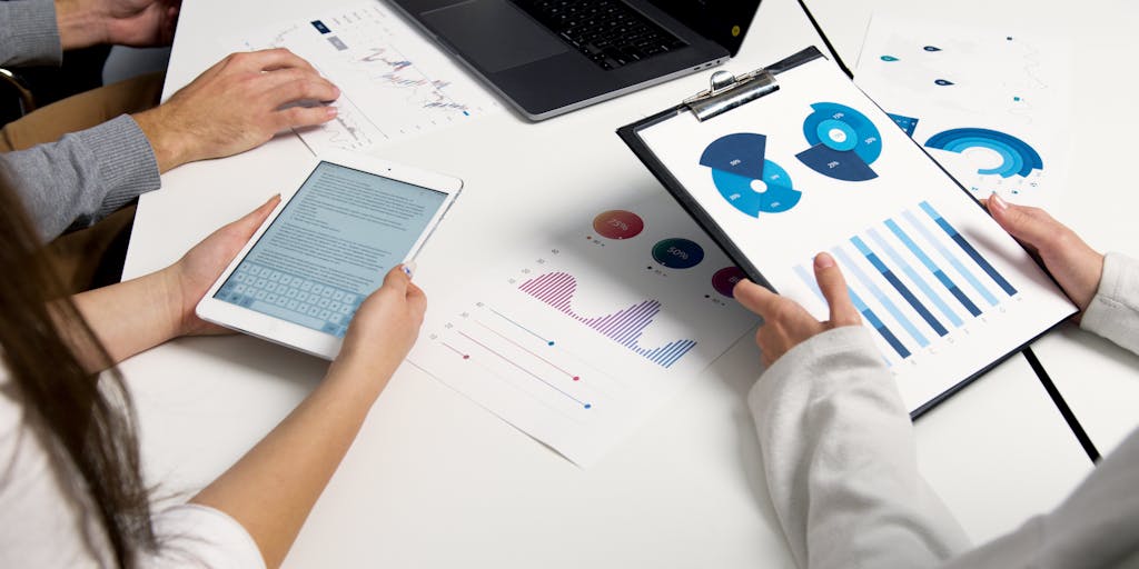 Workspace shot showing a laptop and tablet side-by-side displaying a website mockup with an interactive heatmap and an internal link graph overlay (bubbles and connecting lines). Hands point at the screen as if auditing link placement; modern office lighting, emphasis on UX and analytics tools used for internal link optimization.