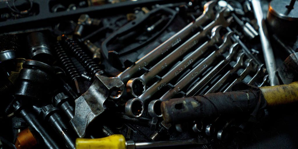 A hands-on workshop scene where two mechanics (or engineers) tune and polish two engines placed on workbenches: one engine has a rocket-style exhaust and a toolbox labeled 