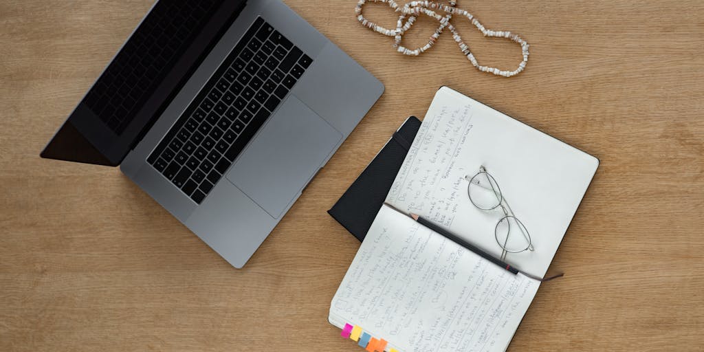 Close-up of a laptop screen showing two overlapping web pages side-by-side with identical paragraphs highlighted in yellow. A hand holds a magnifying glass over the repeated text while sticky notes and a cup of coffee sit blurred in the foreground to create a working-software, investigative mood. Soft natural window light and shallow depth of field emphasize the magnified duplicated content.