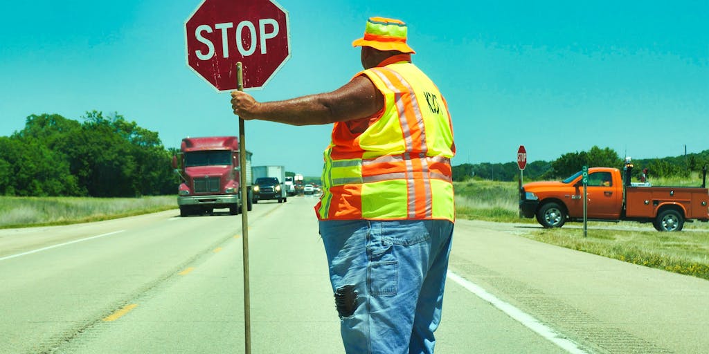 A metaphorical outdoor scene where a highway exit sign reads '301 Redirect' and a worker on a cherry picker is physically turning the sign around to reveal 'Original URL' on the other side; surrounding traffic and blurred cars emphasize motion while the worker's action freezes the moment of changing direction. Bright daylight, high contrast, and a slightly exaggerated oversized road sign for dramatic effect.
