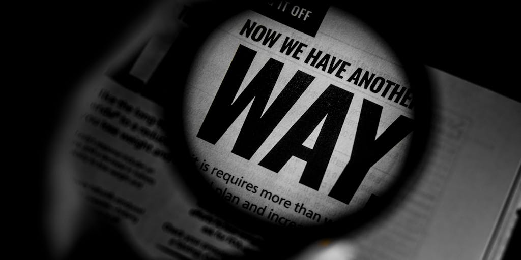 A clean, high-contrast staged photo of a large magnifying glass hovering over a printed search engine results page. The top result is brightly highlighted and sits on a small pedestal labeled “Position 1,” while surrounding results fade into the background. Include a small analytics graph and sticky notes with keywords around the page to show the meaning of SEO position as visibility and ranking.